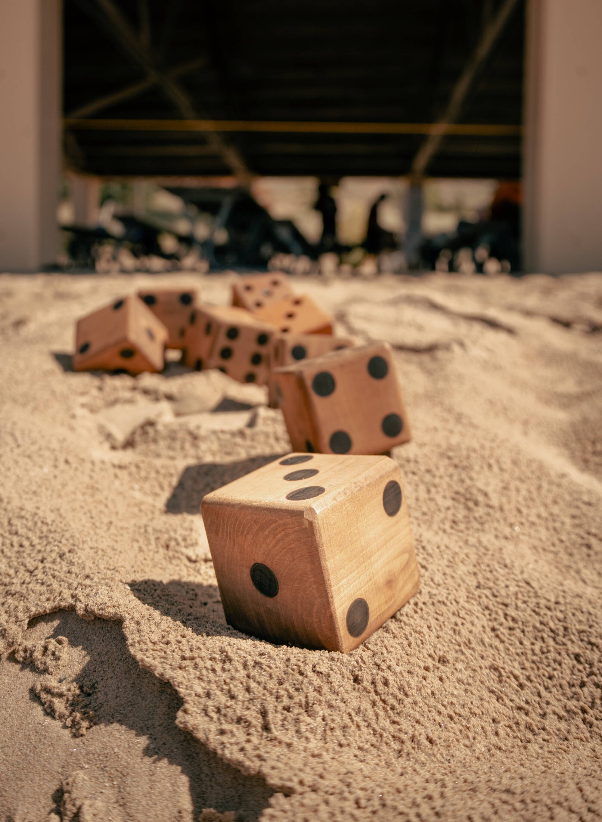 A set of large wooden dice in the sand.
